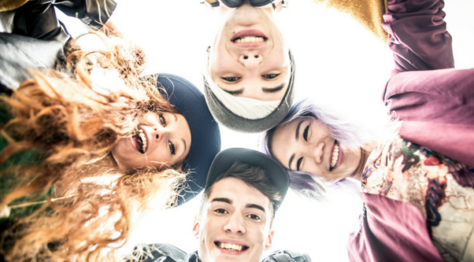 teens in a circle smiling down at camera