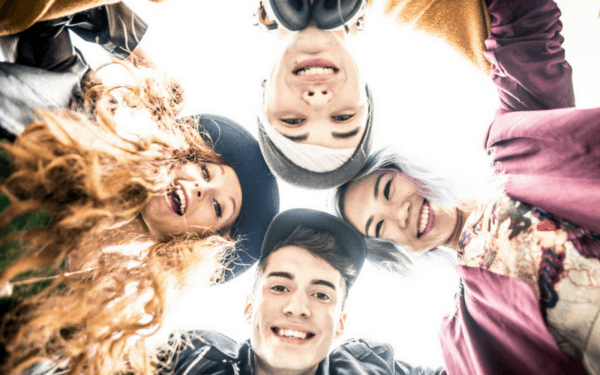 teens in a circle smiling down at camera