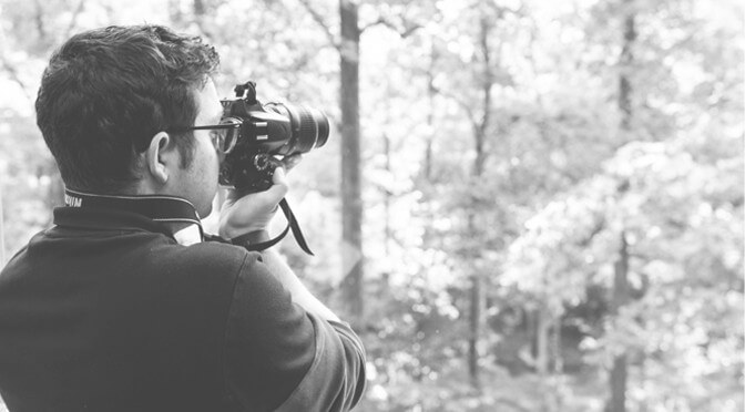 A Hughes Media photographer takes a picture outdoors